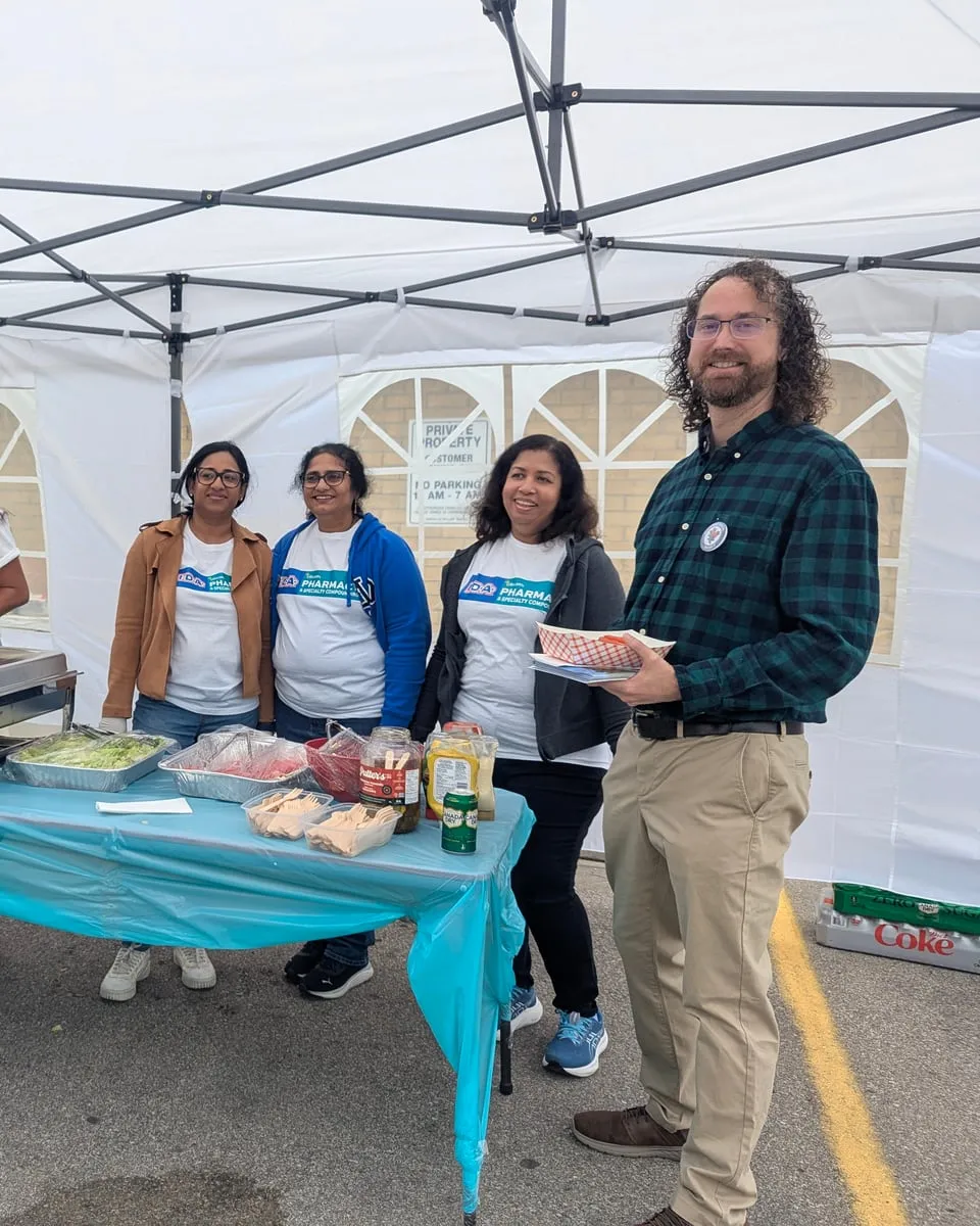 Matt with volunteers serving food under a tent at a community barbecue